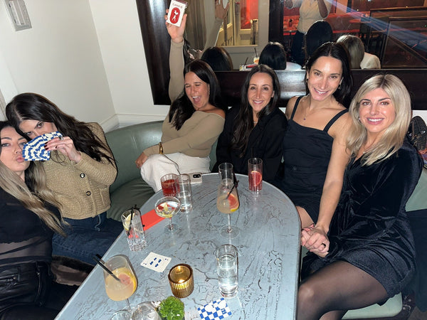 Five friends in a restaurant booth holding up CANDID cards